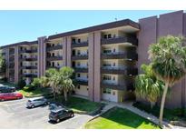Exterior shot of condominium with parking, landscaping, and multi-story covered balconies at 640 N Nova Rd # 117, Ormond Beach, FL 32174