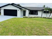 Charming single-story home with a well-manicured lawn, black trim, and a black garage door at 992 Shockney Dr, Ormond Beach, FL 32174
