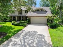 Traditional home boasting a manicured lawn, mature trees, and a two-car garage with brick accents at 1 Crooked Bridge Way, Ormond Beach, FL 32174