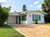 Charming home featuring a brick driveway, well-maintained lawn, and freshly painted white exterior at 33 Camellia Dr, Ormond Beach, FL 32176