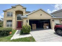 Charming two-story home featuring a red door, a spacious garage, and verdant landscaping at 3660 Daydream Pl, St Cloud, FL 34772