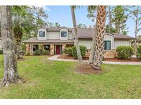 Charming home featuring a stone facade, well-manicured lawn, and inviting landscaping at 428 Pelican Bay Dr, Daytona Beach, FL 32119