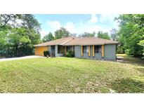 Charming single-story home with well-maintained lawn and vibrant, painted yellow garage door at 1561 Copperfield Ave, Deltona, FL 32738