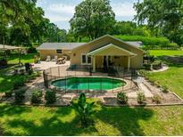 Backyard of home featuring an in-ground fenced pool, brick patio, and well-manicured landscaping at 21375 Nw 150Th Avenue Rd, Micanopy, FL 32667