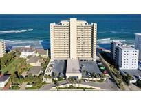 An exterior daytime view of a condo on the beach overlooking the ocean and parking lot with palm trees in the foreground at 89 S Atlantic Ave # 1004, Ormond Beach, FL 32176