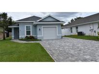 Charming home showcasing a neatly paved driveway and a well-maintained, inviting lawn area at 146 Via Madrid Dr, Ormond Beach, FL 32176