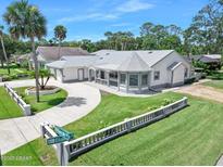 Charming single-story home with a gray roof, circular driveway, and a well-manicured front yard with palm trees at 1650 Riverside Dr, Daytona Beach, FL 32117