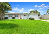 Charming single-story home with a lush green lawn, complemented by vibrant palm trees and a matching attached garage at 1026 Bel Aire Dr, Daytona Beach, FL 32118
