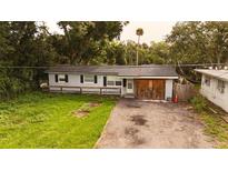 Single-story home featuring a tidy front yard, light blue paint, and a driveway, surrounded by lush trees at 1131 Martha Dr, Daytona Beach, FL 32114