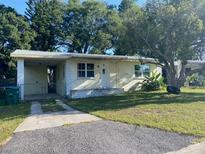 Charming single-story home featuring a carport, well-maintained lawn, and a mature tree providing ample shade at 264 Sherwood Ln, Daytona Beach, FL 32117