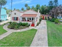 Charming single-story home featuring a beautiful red tile roof, covered porch, and meticulously maintained landscaping at 918 N Wild Olive Ave, Daytona Beach, FL 32118