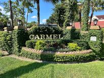 Welcoming Carmel entrance sign with lush greenery, brick accents, and clear blue sky at 1162 Carmel Cir # 100, Casselberry, FL 32707