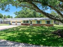 Charming single-story home with yellow siding, brick accents, well-manicured lawn, mature trees, and an attached two-car garage at 1505 Valencia Ave, Daytona Beach, FL 32117