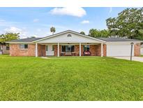 Charming red brick home with a covered front porch and a large, well-manicured lawn at 950 Pineapple Rd, South Daytona, FL 32119