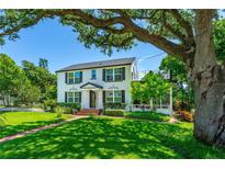Charming two-story home featuring a well-manicured lawn, mature trees, and an inviting brick walkway to the front door at 1221 Gamble Pl, Daytona Beach, FL 32118
