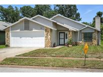 Charming single-Gathering home featuring stone accents, a well-manicured lawn, and an attached two-car garage at 920 N Lakewood Ter, Port Orange, FL 32127