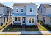 Charming two-story home with a covered porch, well-maintained lawn, and beautiful light blue exterior at 9762 Neruda St, Orlando, FL 32827