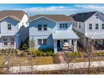 Two-story light blue house with metal roof, front porch, and landscaped yard at 13438 Leggett Aly, Orlando, FL 32827