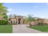 Stunning single-story home showcasing stone accents, a paver driveway, manicured lawn, and lush landscaping at 5418 Meadow Hill Loop, Lady Lake, FL 32159