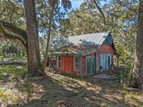 Rustic, two-story home with a metal roof, nestled among trees offering a unique, secluded setting at 13524 Corkwood Ln, Astatula, FL 34705