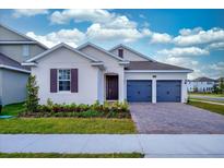 Two-car garage, light beige house with dark shutters and landscaping at 13200 Peaceful Melody Dr, Winter Garden, FL 34787