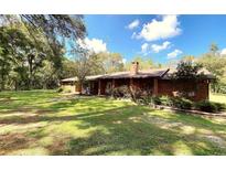 Charming single-story brick home with lush front yard and mature trees, offering a serene setting at 1921 Smitty Rd, Lady Lake, FL 32159