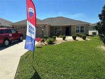 Charming single story home featuring an open sign, manicured lawn, and an inviting walkway at 5596 Cedar Waxwing Dr, The Villages, FL 32163