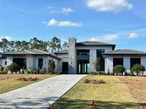 Modern home with gray tile roof and paver driveway at 16122 Pendio Dr, Bella Collina, FL 34756