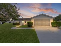 Charming single-story home featuring a well-maintained lawn and an attached two-car garage with screened doors at 17574 Se 106Th Ave, Summerfield, FL 34491