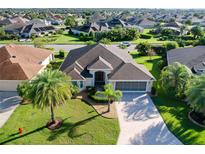 Beautiful single-Gathering home with lush landscaping, mature palm trees, and a wide driveway leading to a screened garage at 1338 Neuport Path, The Villages, FL 32163