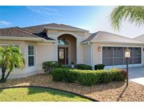 Charming single-story home featuring a beautiful front yard with manicured landscaping and a screened garage at 1338 Neuport Path, The Villages, FL 32163