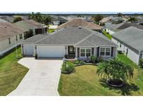 Charming single-story home with a well-manicured lawn, landscaping, and a decorative driveway at 736 Jones Ln, The Villages, FL 32163