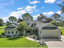 Charming single-story home with lush front yard, mature trees, and two-car garage at 557 Dowling Cir, Lady Lake, FL 32159