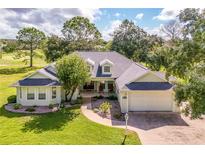 Charming single-story home featuring a well-manicured front lawn, mature trees, and an attached two-car garage at 557 Dowling Cir, Lady Lake, FL 32159