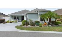 Charming single-story home featuring a beautifully landscaped front yard with lush greenery and a curved driveway at 2968 Wotring Way, The Villages, FL 32163