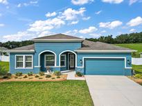 Beautiful teal home with a two-car garage and landscaped yard at 6042 Claystone Way, Mount Dora, FL 32757