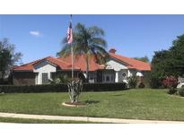 Charming single-story home with a well-manicured lawn, tiled roof, and American flag waving at 39331 Treeline Dr, Lady Lake, FL 32159