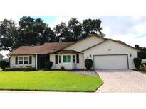 Charming single-story home featuring a manicured lawn and a brick-paved driveway leading to an attached two-car garage at 6410 Tildon Ct, Leesburg, FL 34748