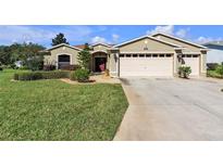 Charming single-story home featuring a well-maintained lawn, two car garage, and lush landscaping at 815 Forest Breeze Path, Leesburg, FL 34748