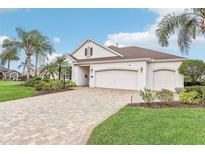 Charming single-story home with a paver driveway, three-car garage, well-kept lawn, and lush tropical landscaping at 1596 Birmingham Ter, The Villages, FL 32162