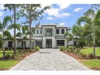 Stately two-story home boasts a symmetrical design, an elegant balcony, lush landscaping, and a paver driveway at 16909 Crete Way, Bella Collina, FL 34756