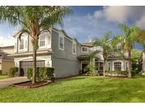 Charming two-story home with a well-manicured lawn and lush landscaping, including palm trees at 13412 Fox Glove St, Winter Garden, FL 34787