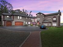 Striking home features a circular driveway, brick accents, a three-car garage and manicured lawn at 6118 Dora Dr, Mount Dora, FL 32757