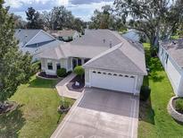 Well-maintained home with a two-car garage, manicured lawn, and mature landscaping in a desirable community at 8288 Se 177Th Winterthur Loop, The Villages, FL 32162