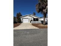 Charming single-story home with attached garage, driveway, and a tidy, landscaped front yard with a white picket fence at 9321 Se 172Nd Augusta Ln, The Villages, FL 32162