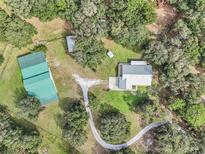 Expansive property showcasing a home, barn, and detached structure amidst lush greenery and mature trees at 3200 Se 20Th Ln, Sumterville, FL 33585