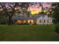 Charming one-story home with manicured lawn and mature trees at sunset at 9345 Silver Lake Dr, Leesburg, FL 34788