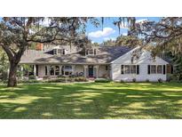 Charming two-story home with a large front yard, mature trees, and intricate detailing on the porch at 9345 Silver Lake Dr, Leesburg, FL 34788