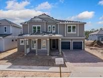 Two-story home with gray siding, two-car garage, and covered porch at 14256 Crest Palm Ave, Windermere, FL 34786