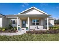 Charming home featuring a covered front porch with beautiful landscaping and a blue front door at 38805 Ranch Gate Blvd, Umatilla, FL 32784